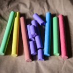 Assorted pastel chalk sticks laid on brown craft paper, some broken pieces visible in the center.