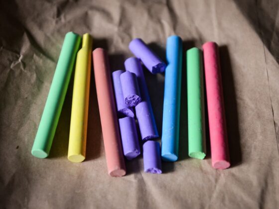 Assorted pastel chalk sticks laid on brown craft paper, some broken pieces visible in the center.
