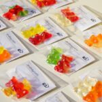 Assorted gummy bear candies in clear packaging laid out on a white surface.